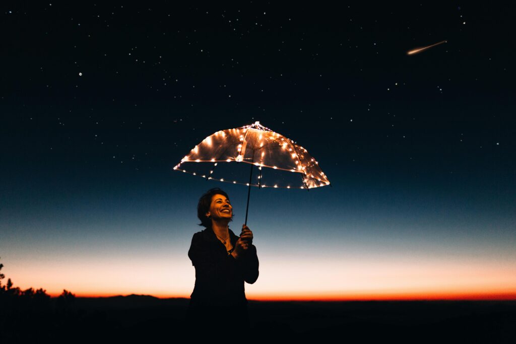 pexels-photo-573238-573238 A joyful woman with a light-up umbrella stands under a starry sky, capturing a magical moment.