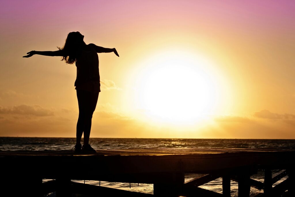 woman-girl-freedom-happy-39853-39853 A joyful silhouette of a woman standing on a dock at sunset, embracing the freedom of nature.
